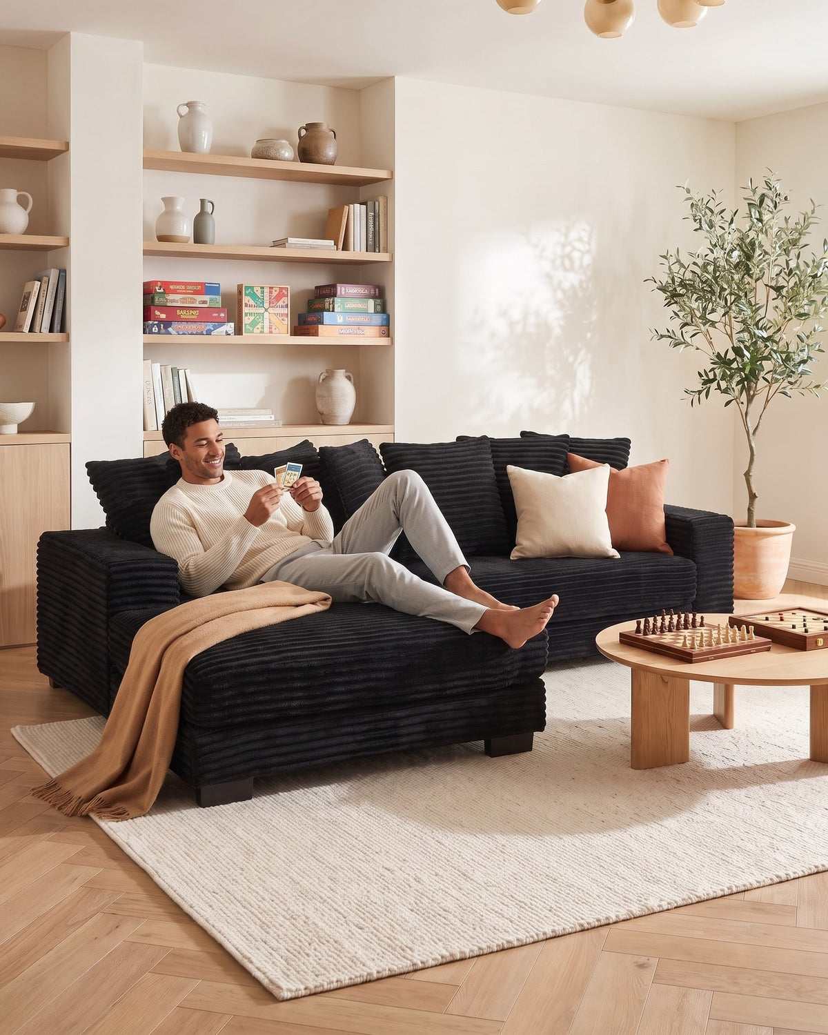 Black Corduroy L-Shaped Sectional with Reversible Chaise, 111 in in Black, chaise shown on the left (reversible), with a person relaxing on it
