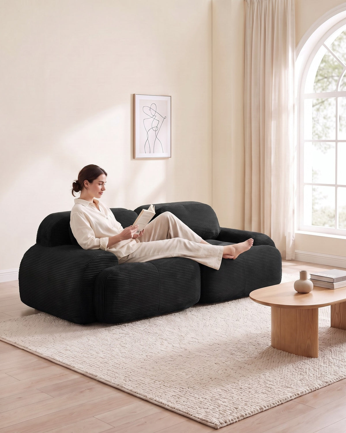 Corduroy Modular Loveseat, 82 in in Black, with a person relaxing on it