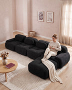 Modular Sofa with Reversible Ottoman, 4 Seats in Black, with a person relaxing on it [c:black] [r:comfort]