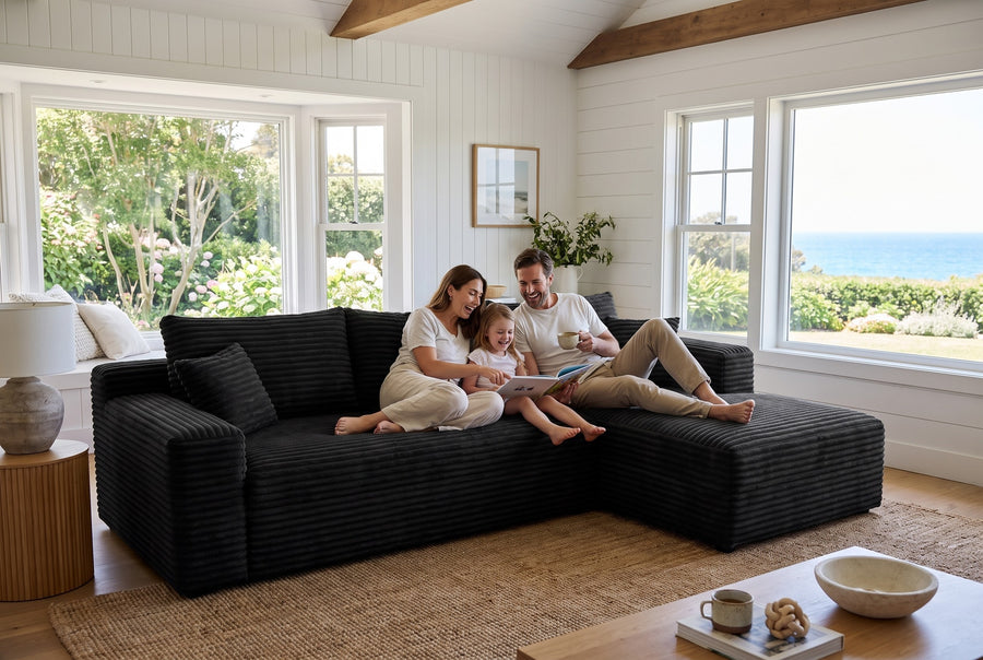 A family with a young child relaxes on a black corduroy L-shaped modular sectional