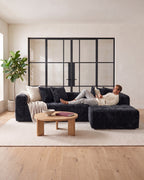 Textured Cloud L-Shaped Sectional with Chaise, 108 in in Black, with a person relaxing on it [c:black] [r:comfort]