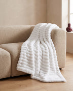 White ribbed faux fur throw draped over a beige sofa